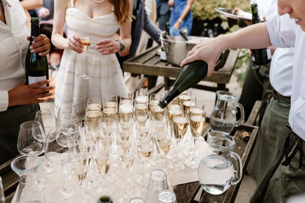 Waiter pours champagne/prosecco on table glasses