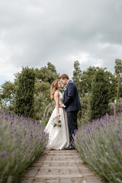 Bride and groom kiss surrounded by bed of flowers