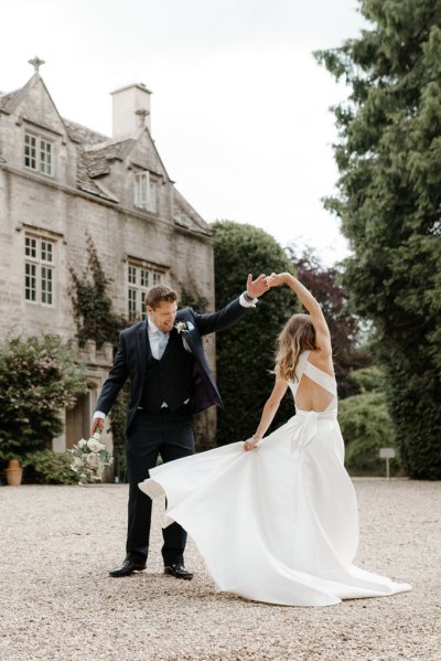 Bride and groom dance outside of wedding venue flowers