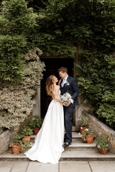 Bride and groom embrace standing in garden