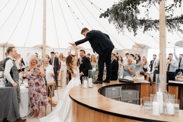 Man standing on top of bar surrounded by guests