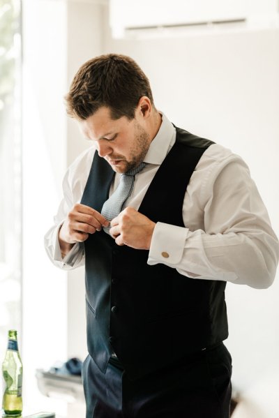 Groom laughing getting ready suit and tie