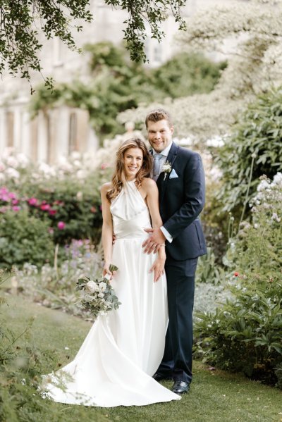 Bride and groom standing in garden holding flowers