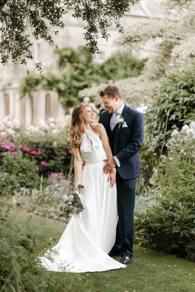 Bride and groom standing in garden holding flowers