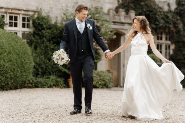 Bride and groom walk outside wedding venue holding hands