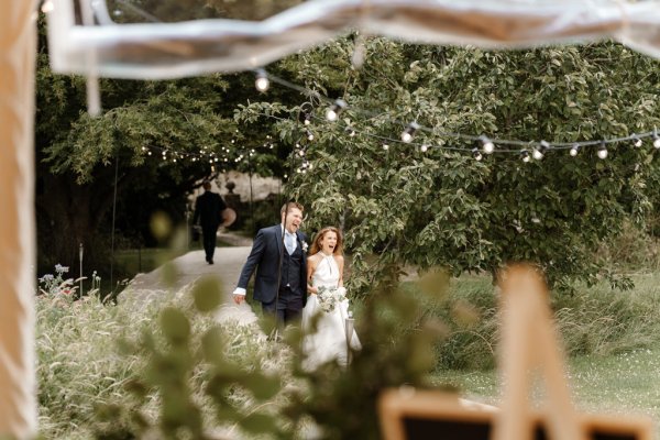 Bride and groom walk through garden