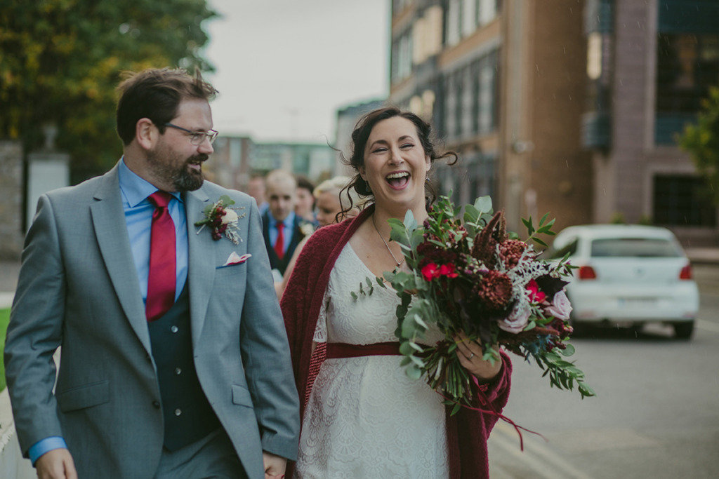 Bride and groom walking outside holding bouquet of flowers