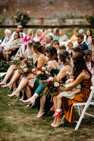 Guests sitting at front holding flowers bridesmaids