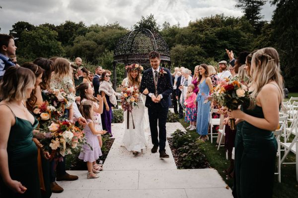 Bride and groom exit ceremony guests clap