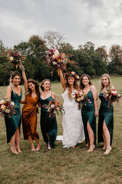 Bride and bridesmaids on grass with bouquet of flowers