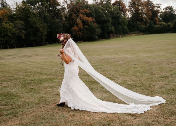 bride with roses flowers in her hair on grass dress detail veil