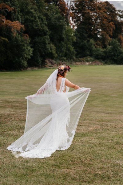 bride with roses flowers in her hair on grass dress detail veil