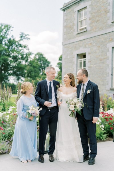 Bride and bridesmaid holding flowers family groom