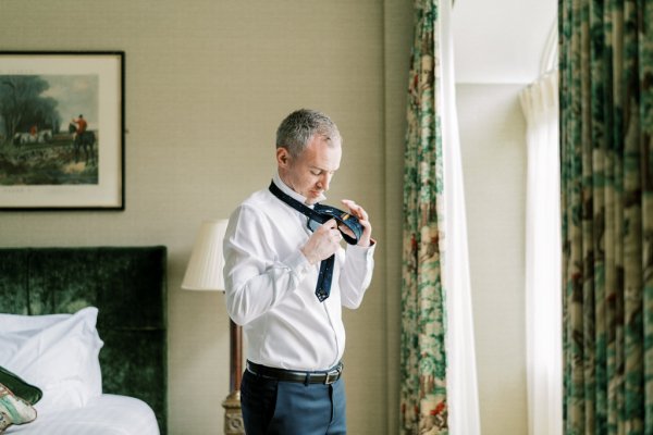 Groom puts on shirt and tie