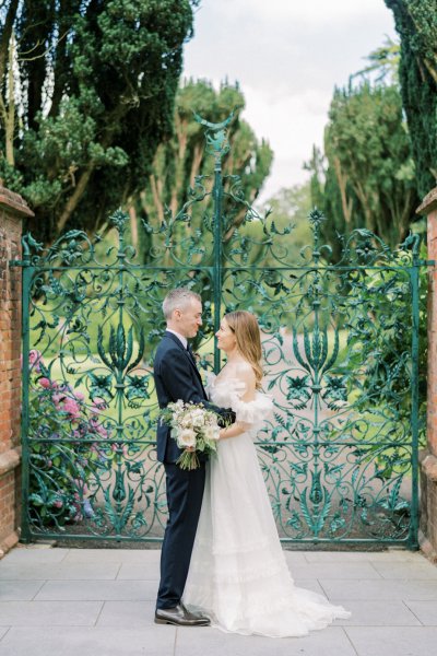 Bride and groom in front of flower gate embracing hugging