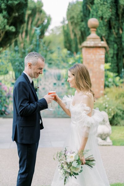 Couple cheers with cocktails/prosecco or champagne in garden