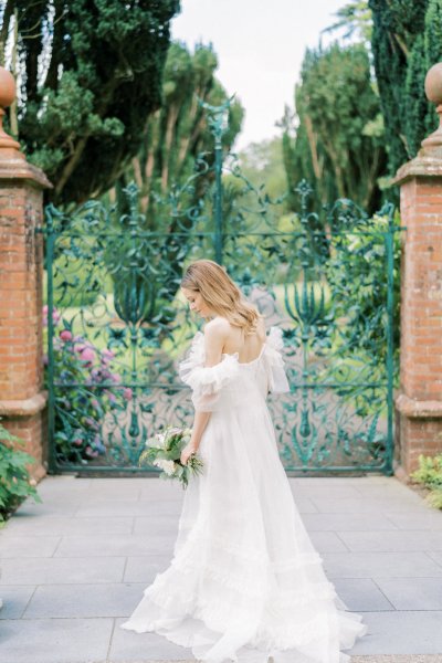 Bride on her own in front of flower gate