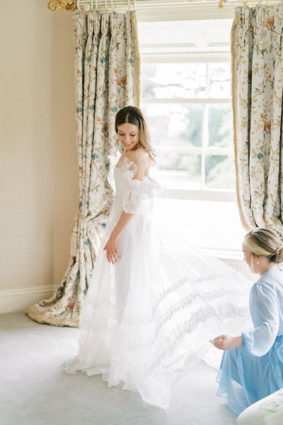 Mother bridesmaid helps bride with dress