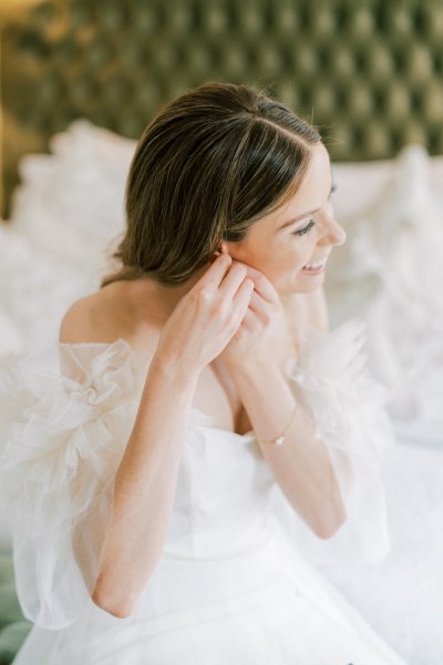 Bride putting on pearl earrings