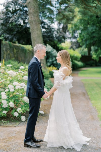 Bride and groom hold hands in garden