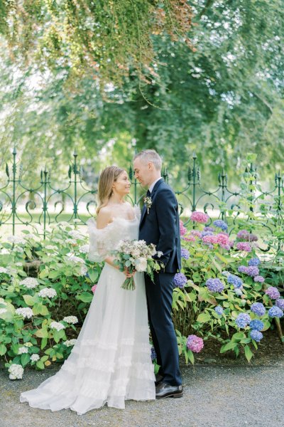 Bride and groom look at each other bouquet/flowers go in for a kiss