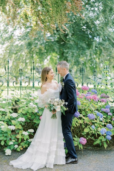 Bride and groom look at each other bouquet/flowers go in for a kiss