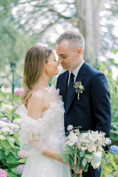 Bride and groom look at each other bouquet/flowers go in for a kiss