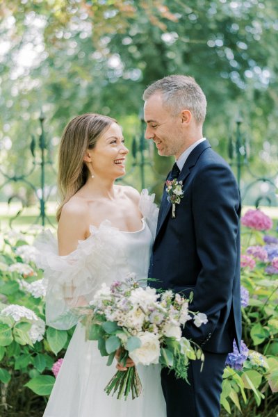 Bride and groom look at each other bouquet/flowers