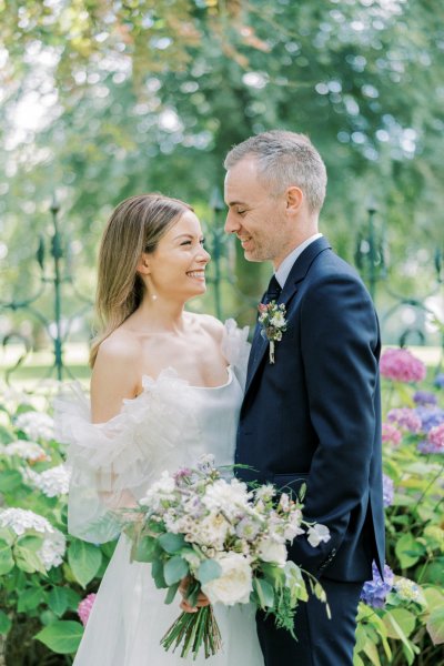 Bride and groom look at each other bouquet/flowers