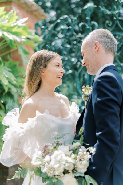 Bride and groom look at each other bouquet/flowers