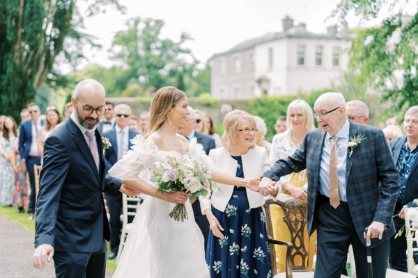 Bride holding white bouquets/flowers and family/guests