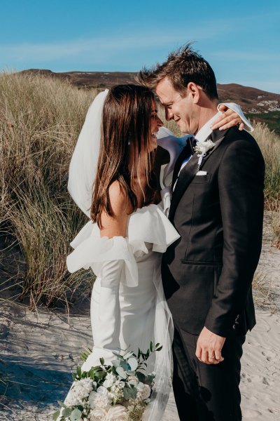 Bride and groom kiss on the beach