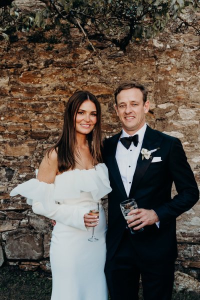 Bride and groom face the camera holding glass of champagne