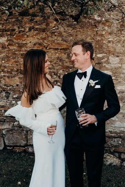 Bride and groom face each other holding glass of champagne