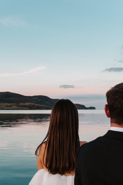 Scenic background lake ocean view with bride and groom looking at landscape