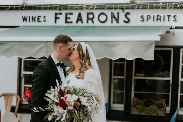 Bride amd groom kiss kissing outside of Fearons pub