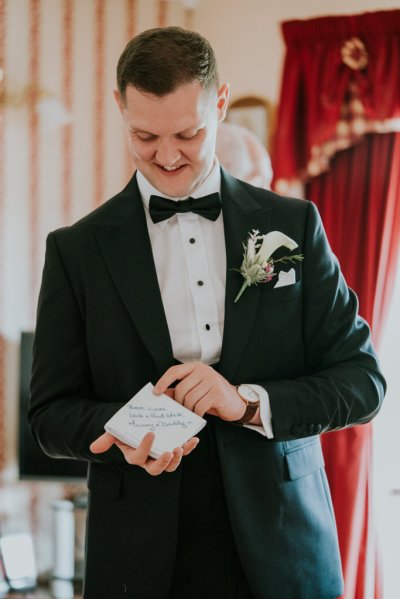 Groom holding gift black suit