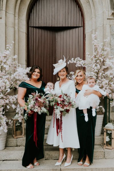 Bridesmaids mother two baby girls surrounded by flowers