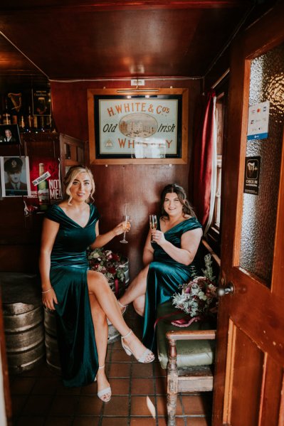 Bridesmaids in green satin dresses holding champagne glasses