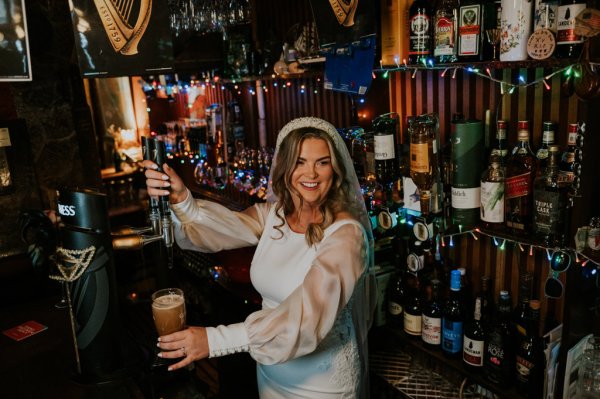 Bride pouring pint of Guinness beer pub veil