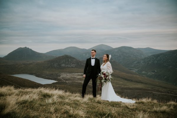 Bride and groom on mountain landscape lake and fog rocks sky view