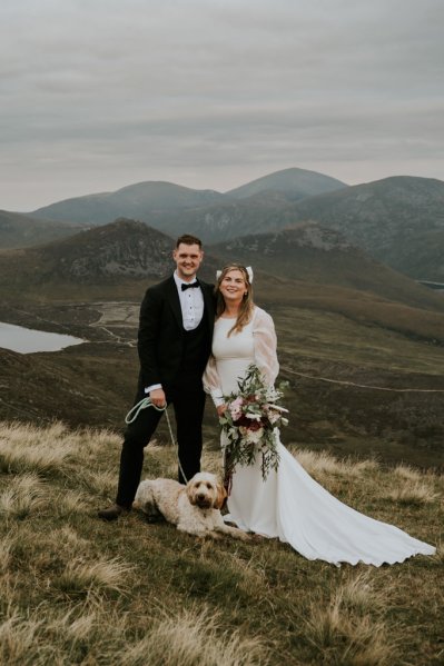 Bride and groom on mountain landscape lake and fog rocks sky view with dog