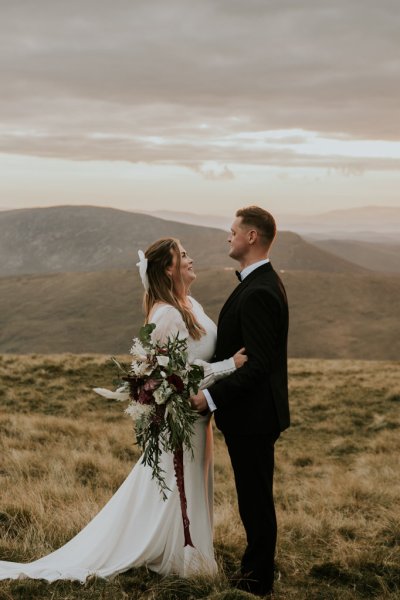 Bride and groom on mountain landscape lake and fog rocks sky view