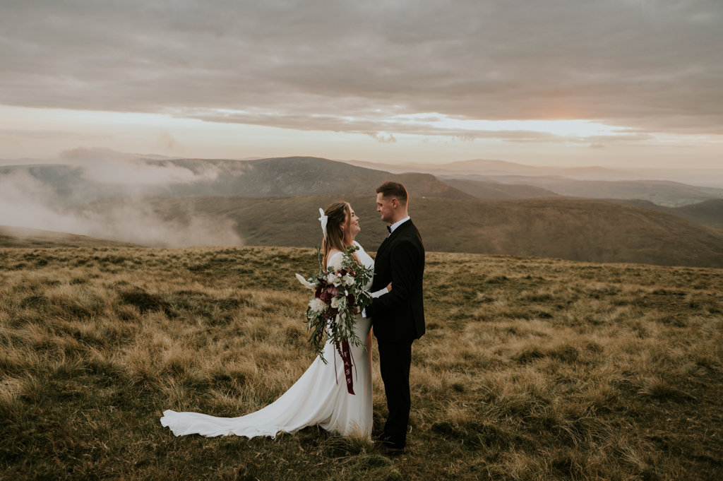 Bride and groom on mountain landscape lake and fog rocks sky view