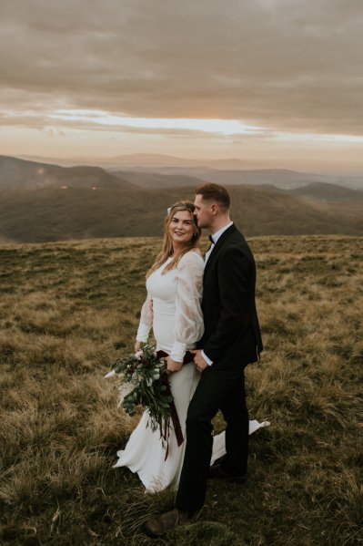 Bride and groom on mountain landscape lake and fog rocks sky view