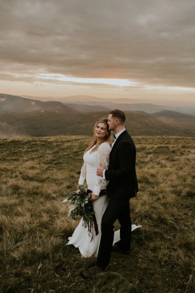 Bride and groom on mountain landscape lake and fog rocks sky view