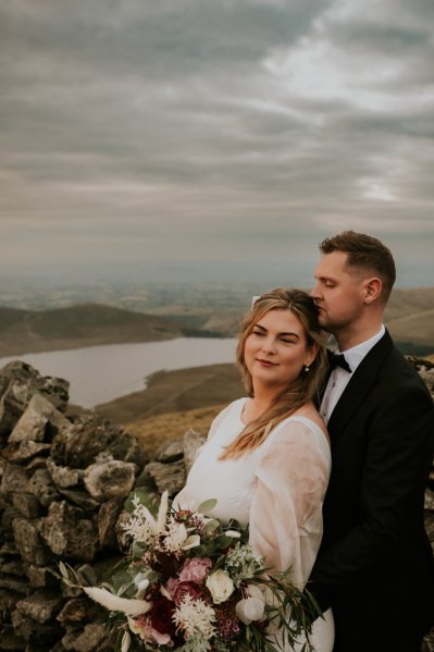 Bride and groom on mountain landscape lake and fog rocks sky view