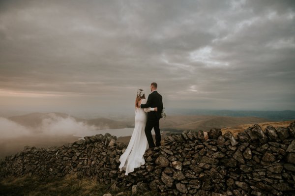 Bride and groom on mountain landscape lake and fog rocks sky view