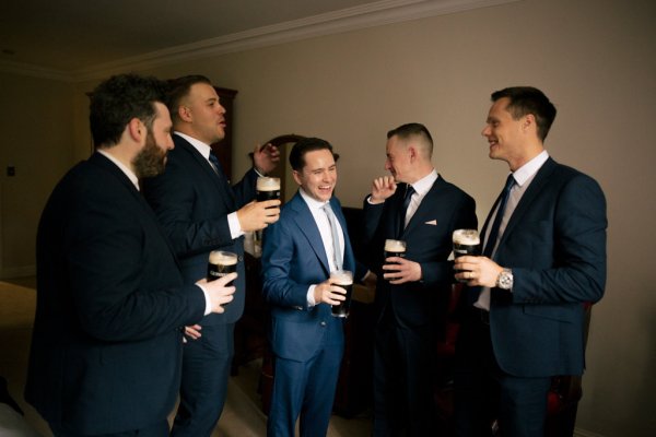 Groom and groomsman drinking Guinness