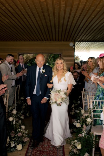 Father of the bride walks down the aisle guests clap